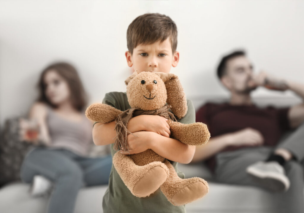 Little boy hugging stuffy with parents neglecting on couch