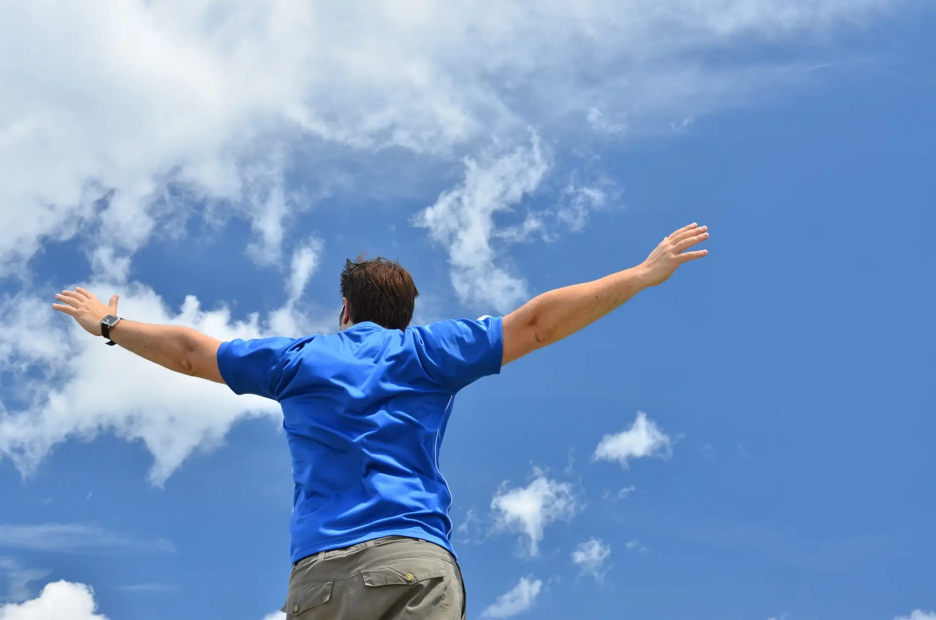 Man in blue shirt on blue sky with white clouds